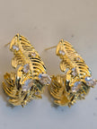 Close-up side view of gold-plated feather earrings showing sculpted barb detail and clear zirconia clusters
