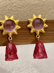 Pair of gold sun earrings with pink stone centres and rose-bud drops displayed upright on a wooden jewellery stand