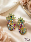 Pair of gold-plated multicolour crystal pineapple stud earrings laid flat on ivory satin fabric