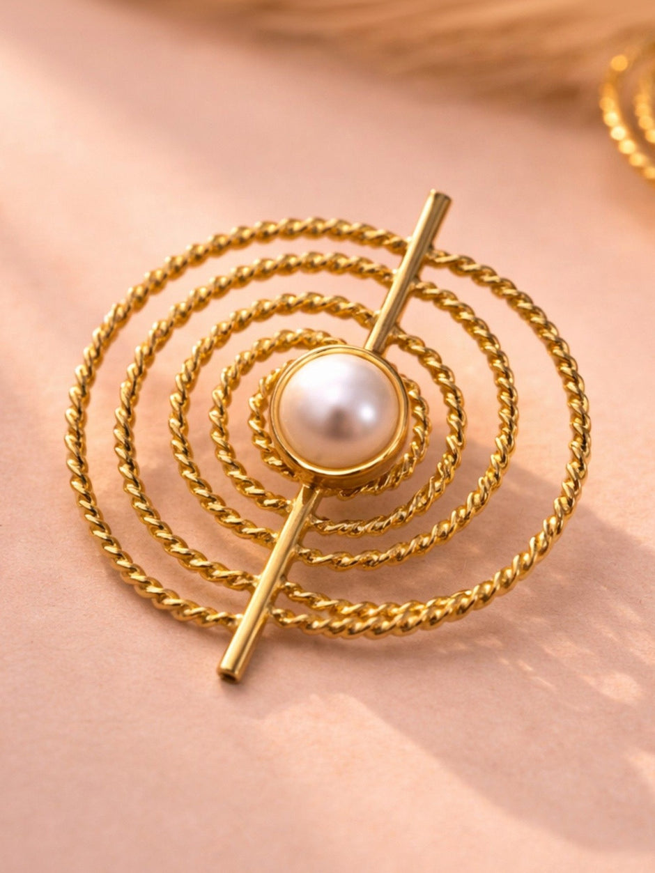 Single gold-plated spiral rope stud earring with faux pearl centre on a pink surface