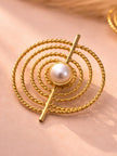 Single gold-plated spiral rope stud earring with faux pearl centre on a pink surface