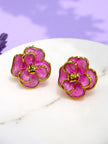 Pair of gold-plated pink enamel flower stud earrings on a white marble surface with a lavender background