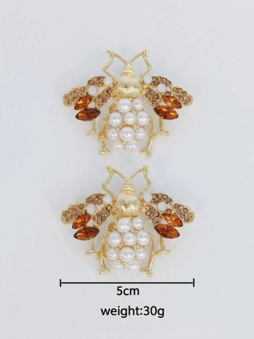 Flat lay of a pair of bee stud earrings with size reference showing approximately 5 cm width and 30 g weight