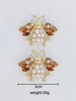 Flat lay of a pair of bee stud earrings with size reference showing approximately 5 cm width and 30 g weight