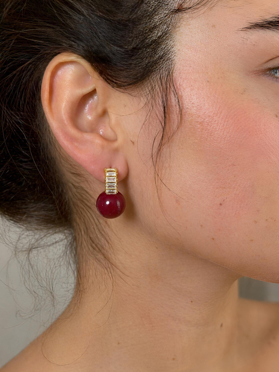 Gold-plated red ball baguette crystal stud earring worn on a model's ear showing side profile and fit