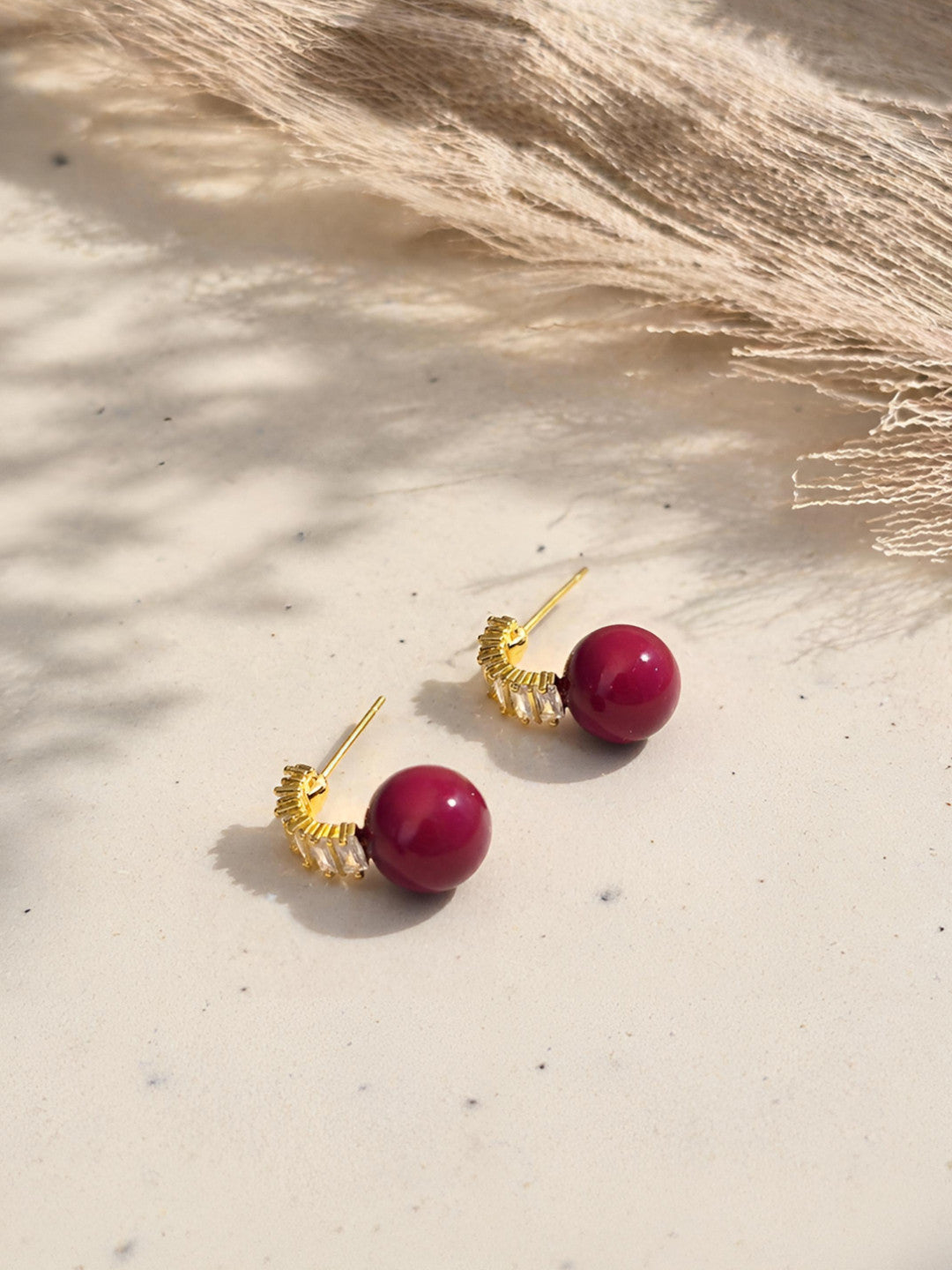 Side view of red sphere drop earrings with gold baguette crystal bar showing the push-back pin and stud construction