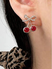 Single cherry bow drop earring worn on a model's ear with dark hair and leopard-print top