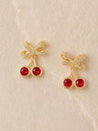Two cherry crystal drop stud earrings displayed on a light textured fabric surface