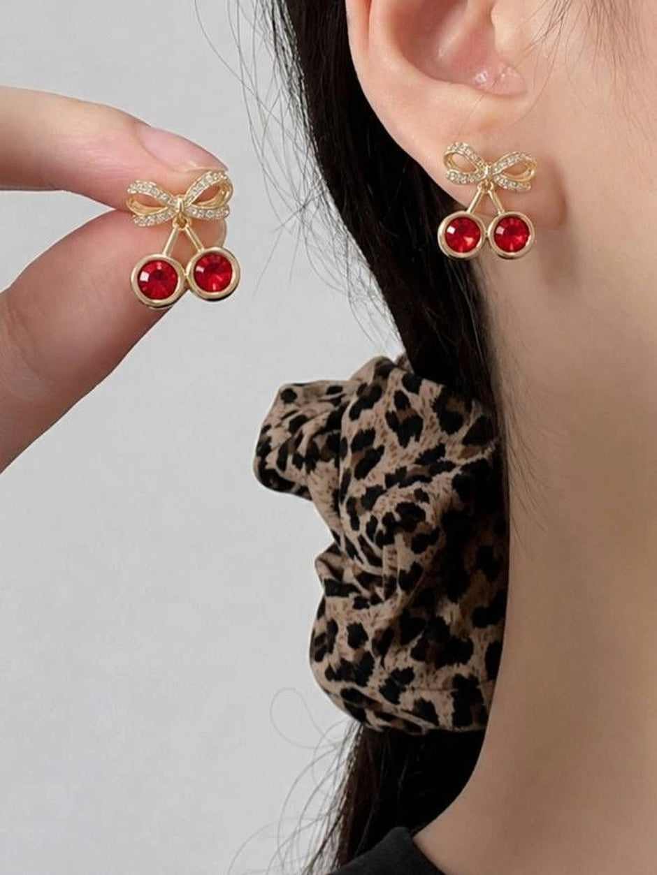 Cherry crystal bow stud earring worn on a model's ear alongside a leopard-print scrunchie