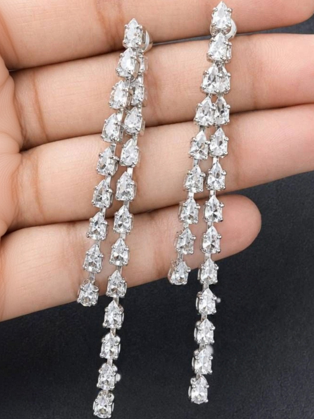 Both silver CZ long drop earrings held in a palm showing full length and detail