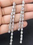 Both silver CZ long drop earrings held in a palm showing full length and detail