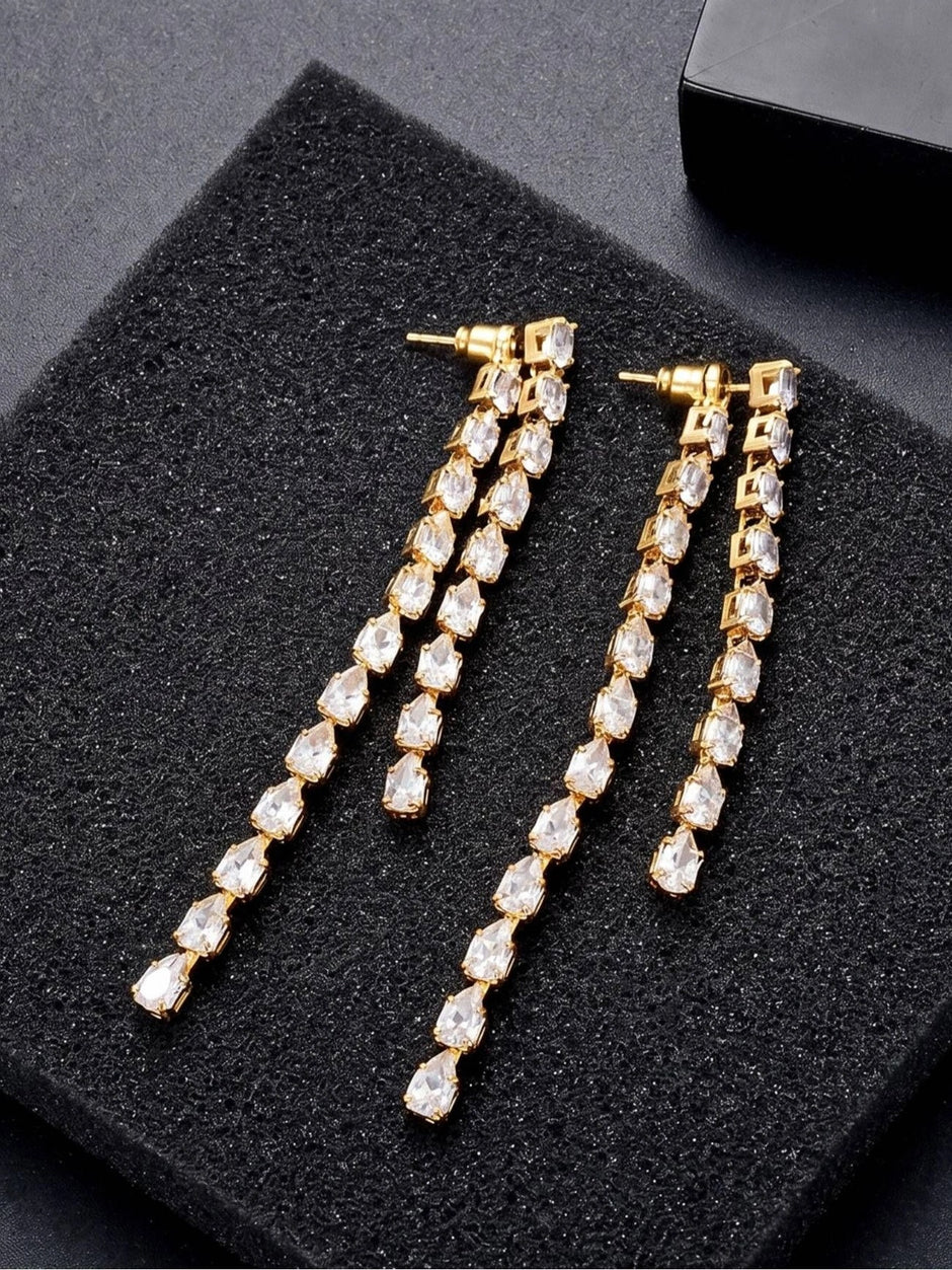 Pair of gold-plated CZ teardrop long drop earrings laid flat on a black foam display tray
