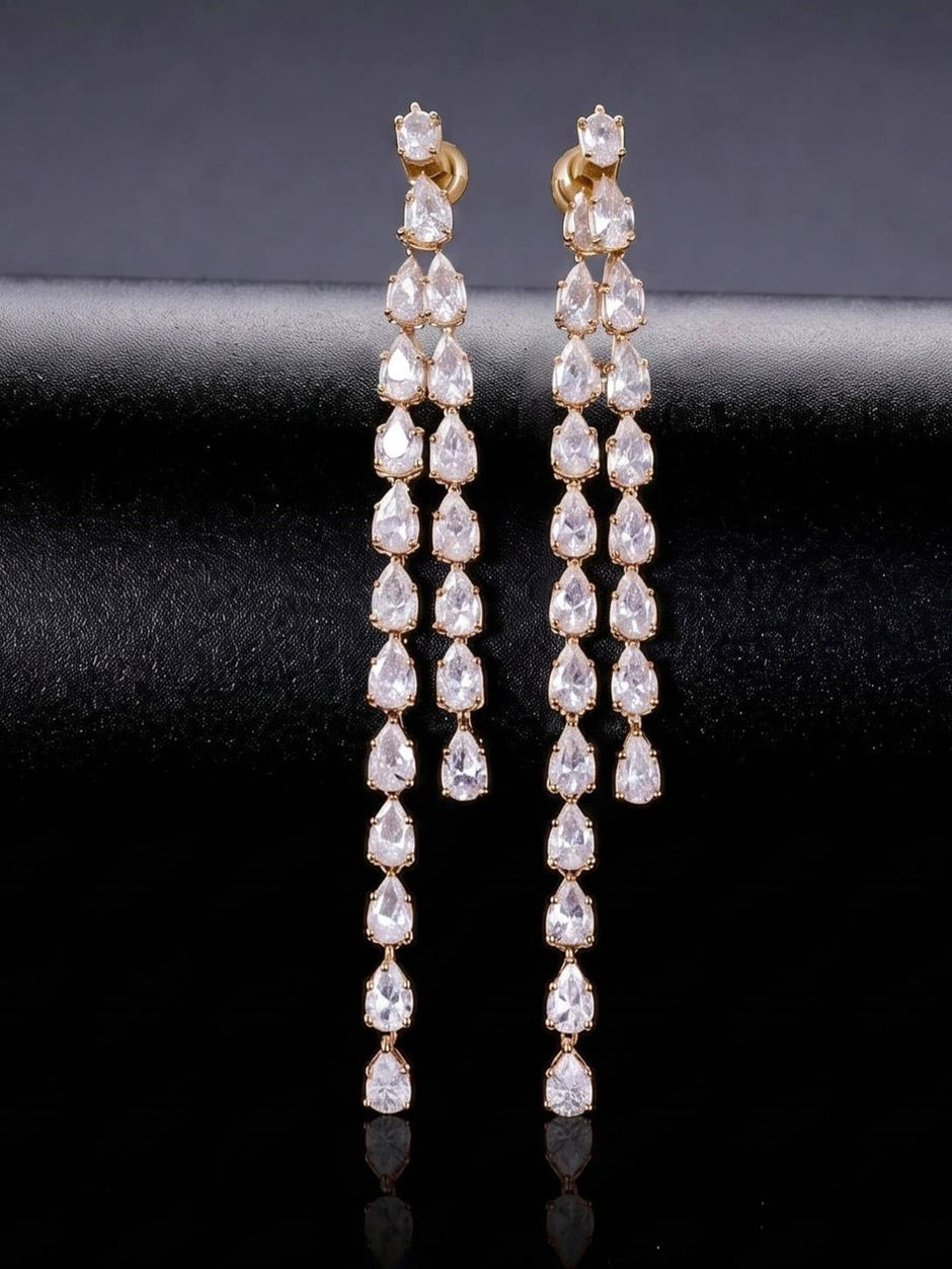 Front view of both gold-plated pear-cut CZ drop earrings standing upright on black satin surface