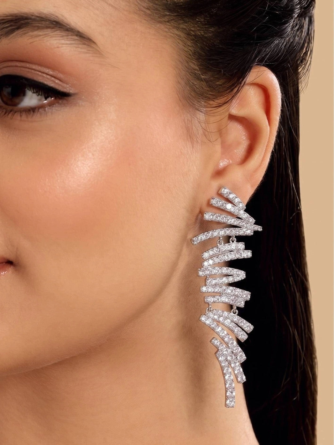 Model wearing silver CZ spiral bar drop earring on right ear against a neutral beige background