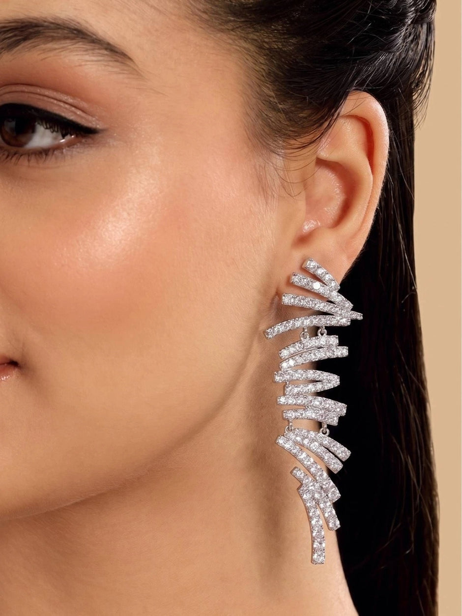 Model wearing silver CZ spiral bar drop earring on right ear against a neutral beige background