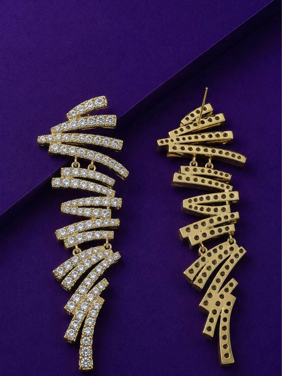 Front and back view of gold-plated zigzag bar drop earrings on purple surface showing stud post
