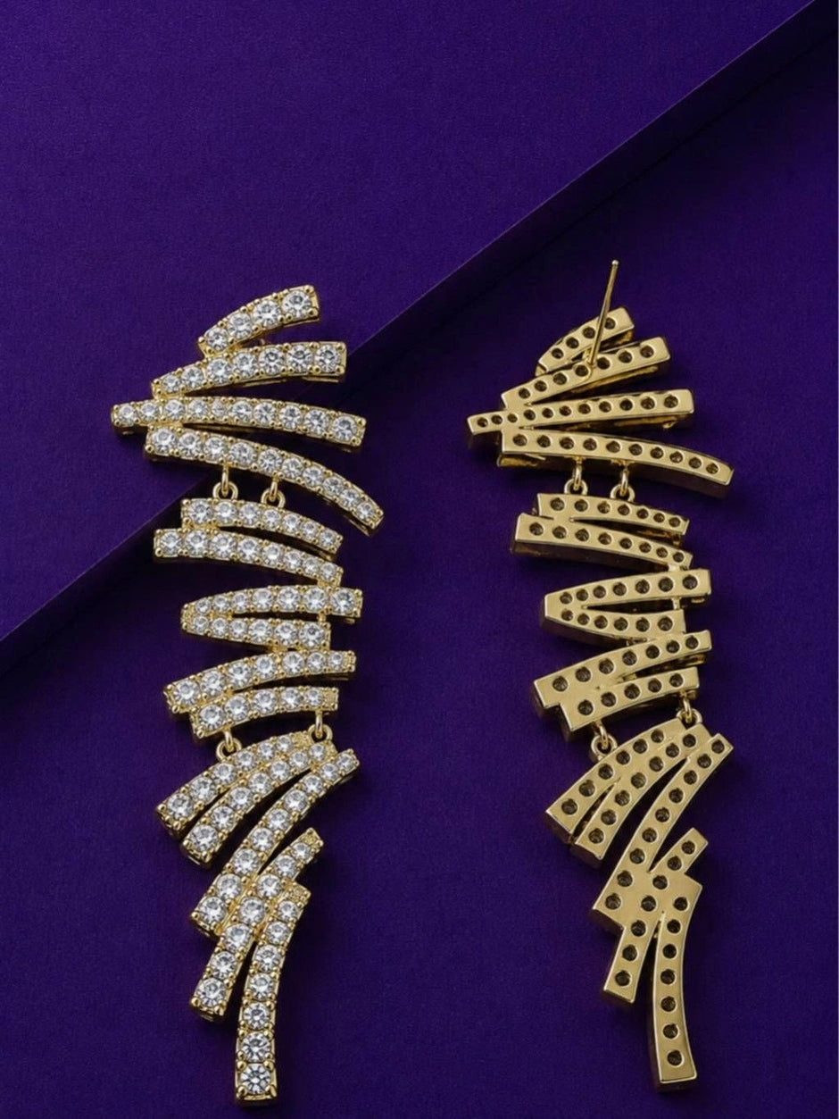 Front and back view of gold-plated zigzag bar drop earrings on purple surface showing stud post