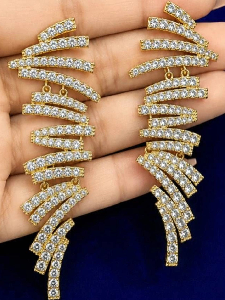 Both gold-plated crystal rhinestone drop earrings held in an open palm against blue background