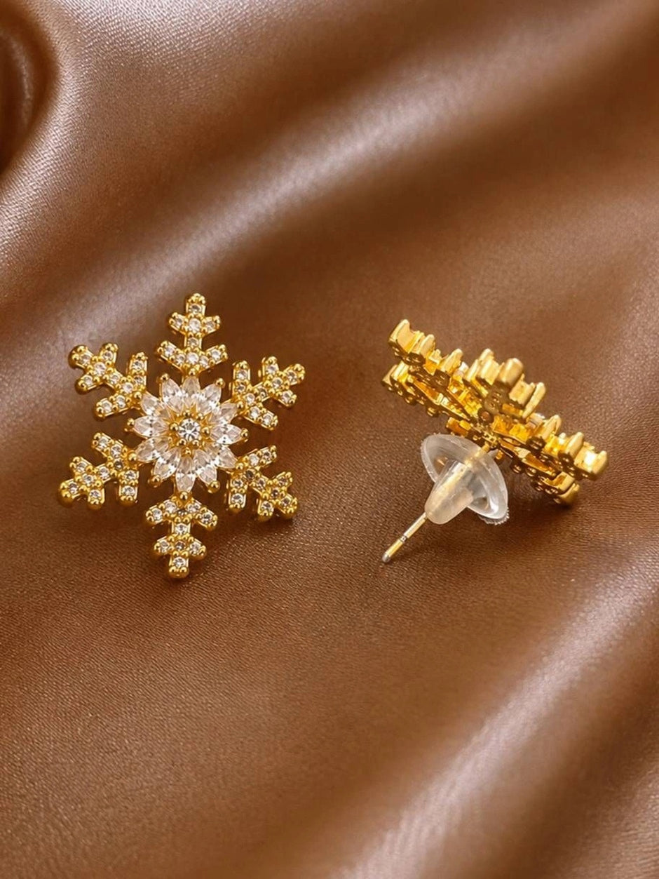 Front and back view of gold-plated snowflake stud earring with push-back butterfly closure on satin fabric