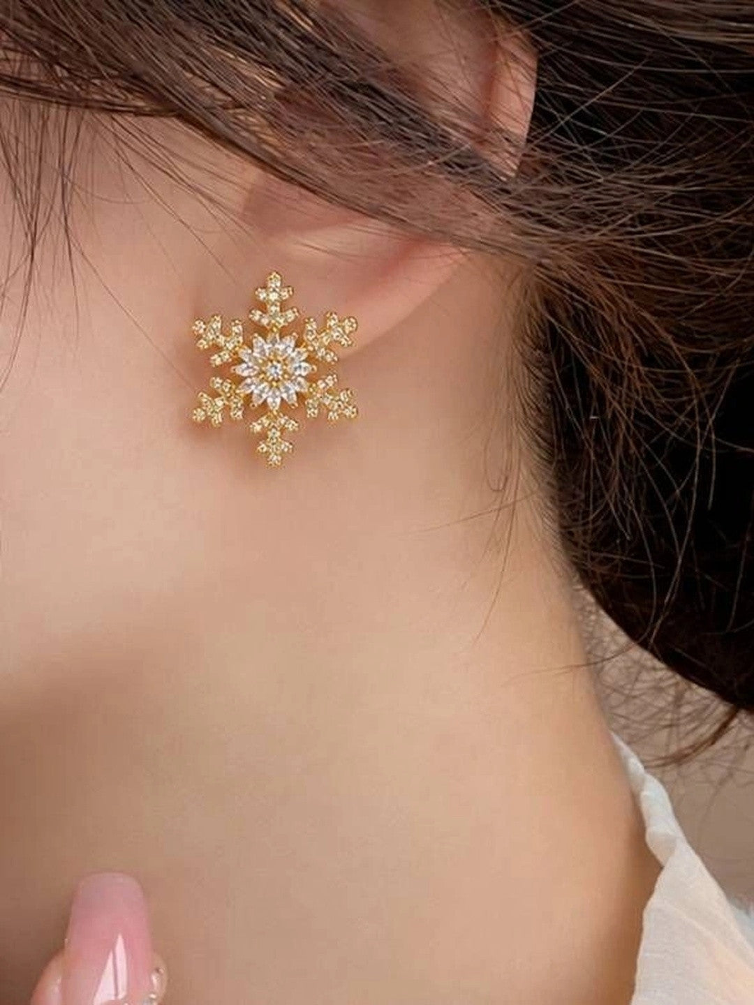 Gold-plated snowflake CZ stud earring worn on a woman's ear showing scale and fit