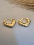 Pair of gold-plated chunky square hoop earrings with brushed matte finish on white marble surface
