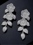 Two silver pavé CZ floral earrings laid flat on a dark surface showing full drop length