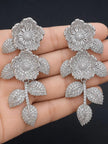 Pair of large silver CZ floral drop earrings held in an open palm for size reference