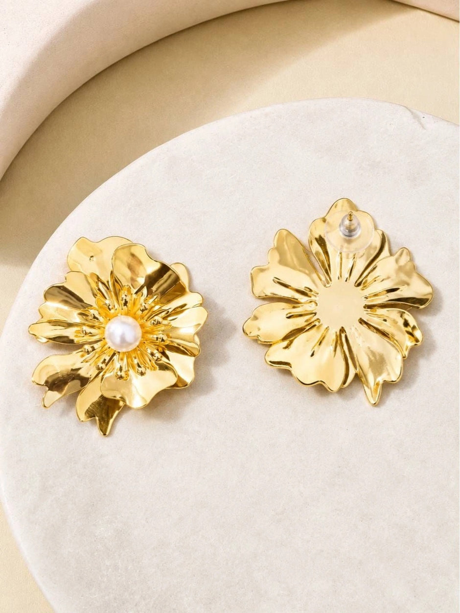 Front and back view of gold-plated floral stud earrings with faux pearl centre on a white stone surface