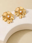 Pair of gold-plated layered petal stud earrings with pearl centres displayed on a curved white prop