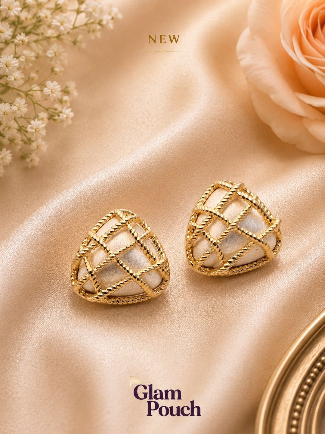 Pair of gold vermeil heart stud earrings with pearl inlay on champagne satin fabric beside a peach rose