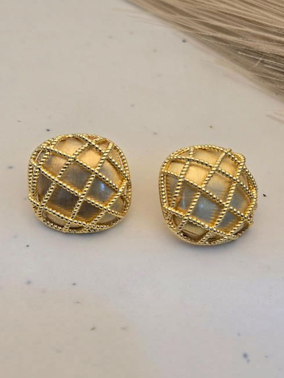 Pair of gold-plated dome stud earrings with mother of pearl inlay and beaded lattice detail on a cream surface