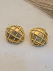 Pair of gold-plated dome stud earrings with mother of pearl inlay and beaded lattice detail on a cream surface