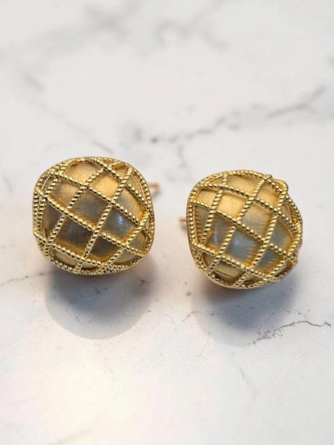 Gold lattice dome stud earrings with iridescent shell inlay displayed on a white marble background