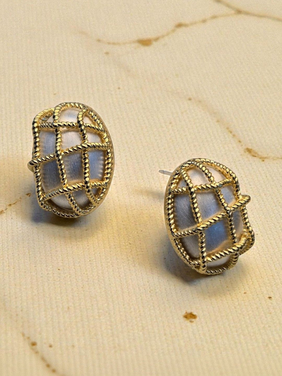 Pair of gold-plated twisted rope cage oval stud earrings on a cream fabric surface