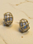 Pair of gold-plated twisted rope cage oval stud earrings on a cream fabric surface