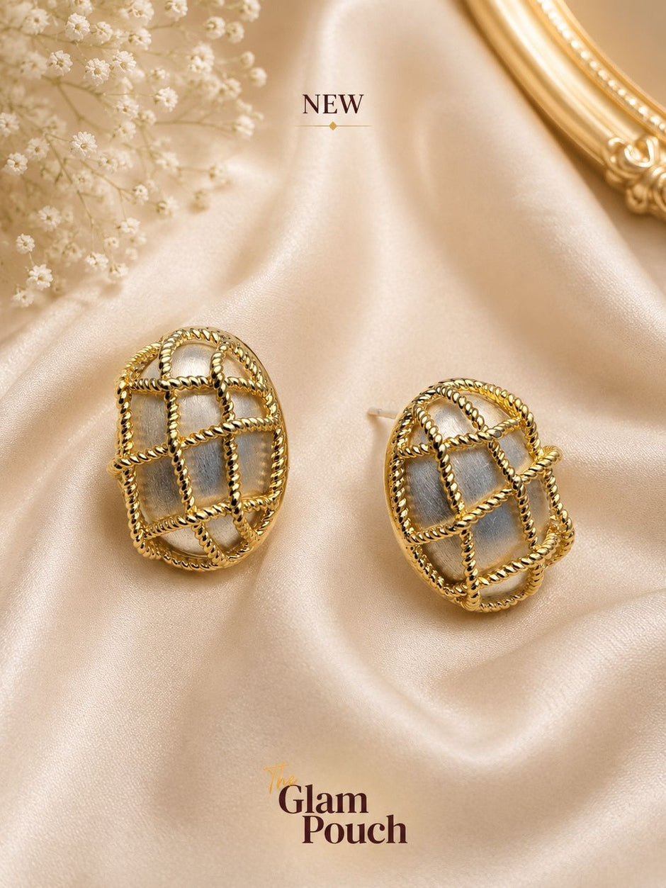 Two gold twisted cage oval studs displayed on champagne satin with baby's breath flowers