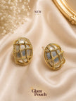 Two gold twisted cage oval studs displayed on champagne satin with baby's breath flowers