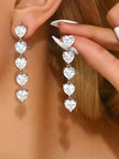 Model wearing silver cascading heart drop earrings, one earring in ear and one held up to show length