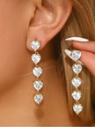 Gold-plated heart CZ drop earrings worn on a model's ear, showing full length cascade of five clear crystal hearts