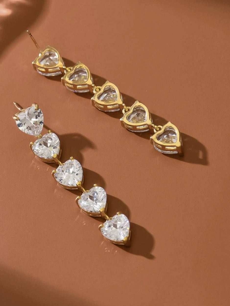 Side-profile view of heart drop earrings on terracotta background, revealing gold prong settings and stone depth