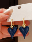 Pair of navy blue enamel heart hoops displayed on white earring card held in hand