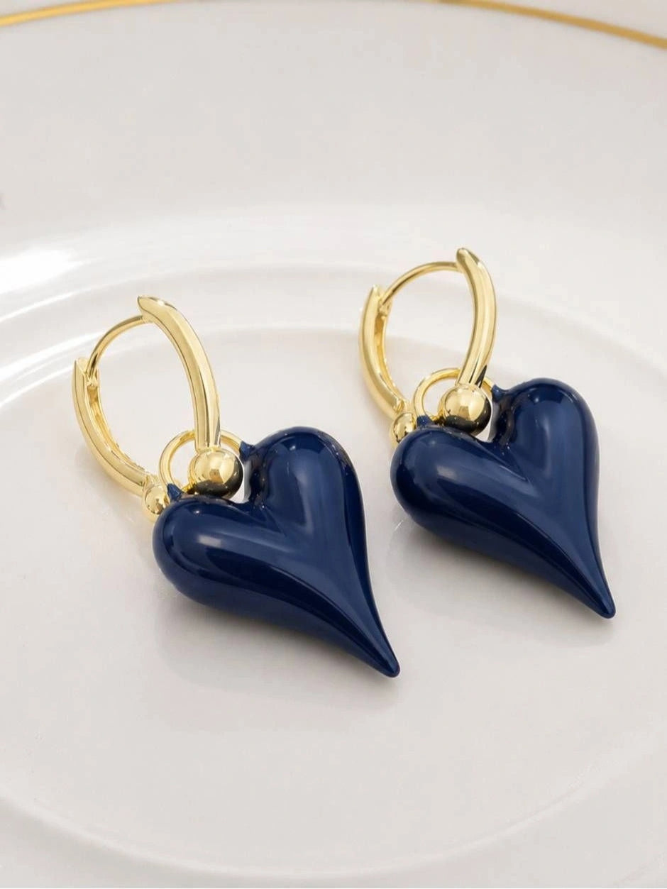 Navy blue enamel heart drop hoop earrings laid flat on white ceramic plate