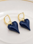 Navy blue enamel heart drop hoop earrings laid flat on white ceramic plate