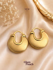 Pair of gold-tone chunky disc hoop earrings laid flat on cream satin fabric with dried flowers