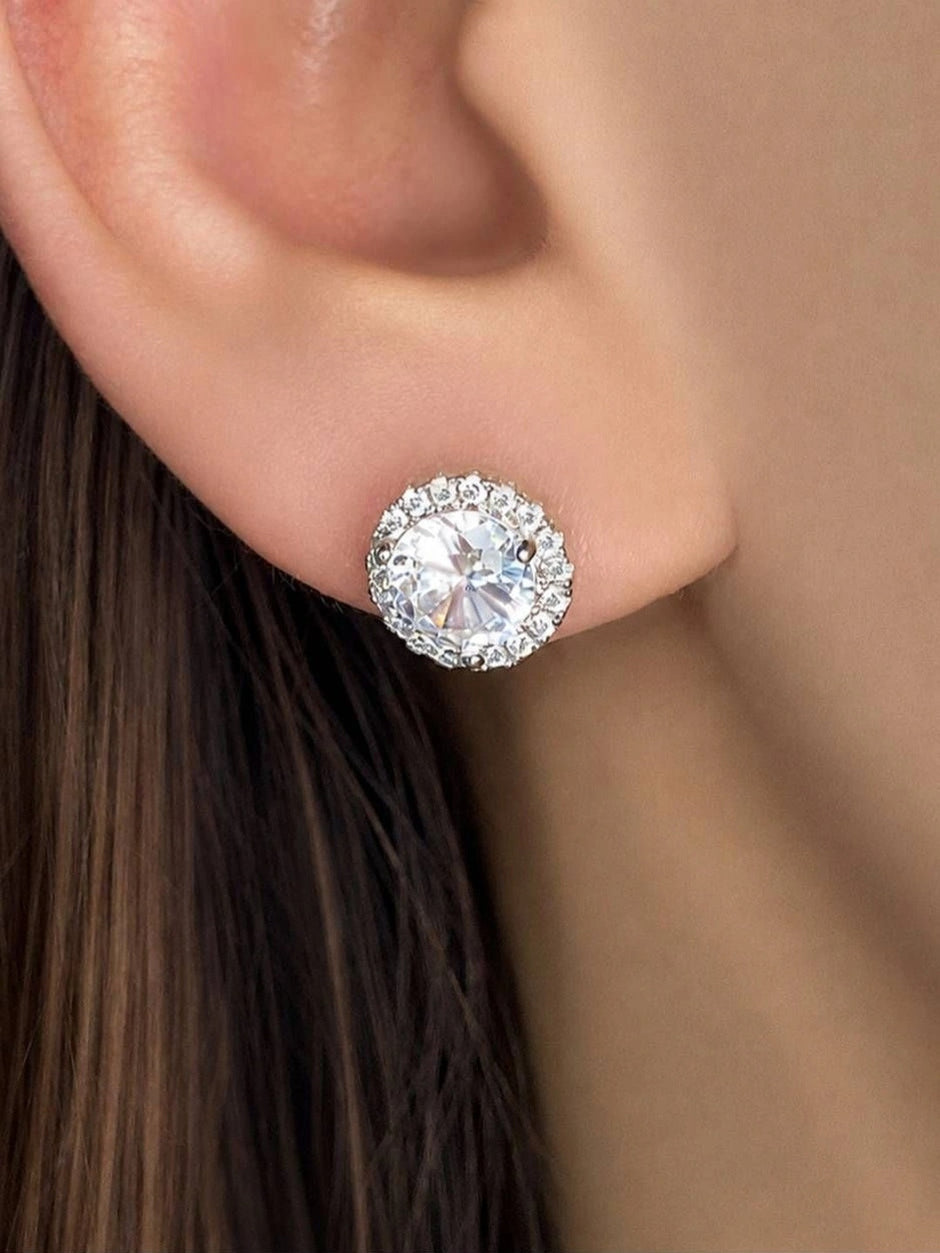 Silver-finish CZ halo stud earring worn on a woman's ear, showing size and sparkle against hair