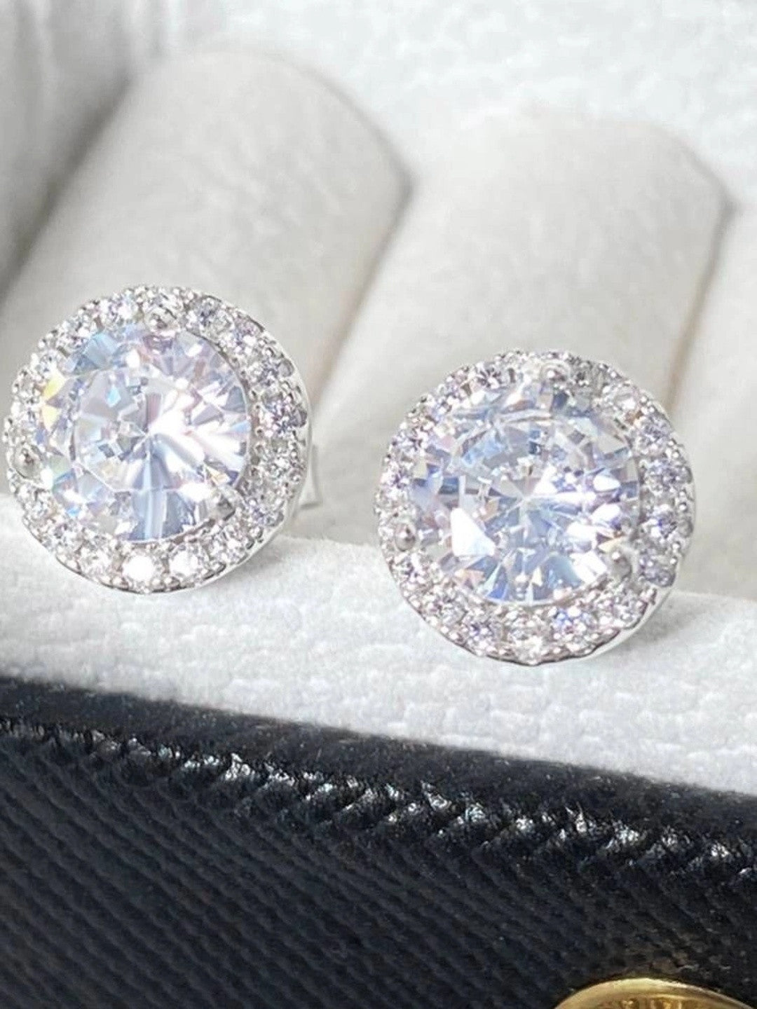 Pair of CZ halo stud earrings displayed side by side in a jewellery box with white cushion lining