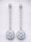 Pair of silver CZ halo drop earrings laid flat on a white marble surface showing full length