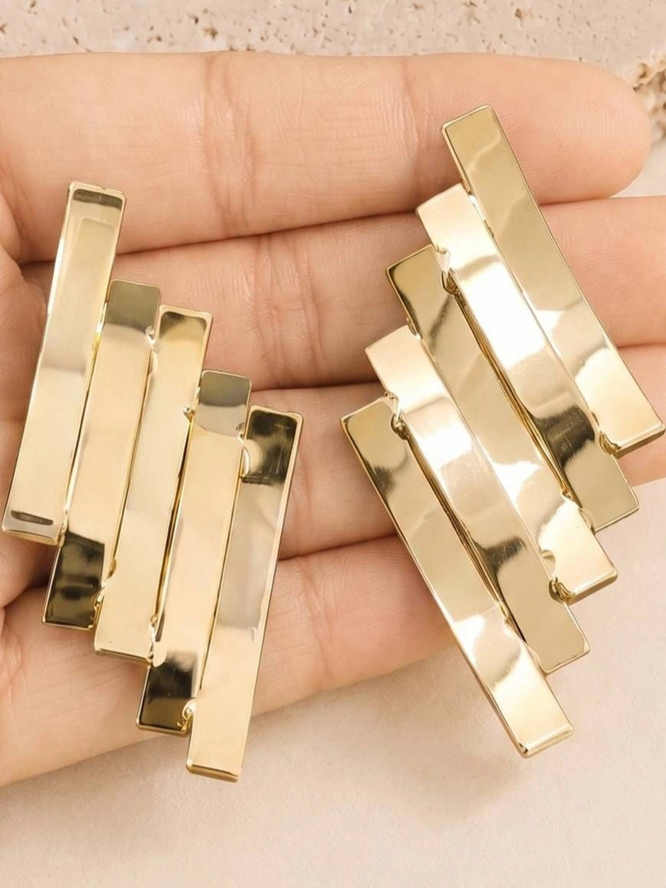 Both gold-toned stacked bar earrings held in an open palm showing size and detail
