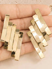 Both gold-toned stacked bar earrings held in an open palm showing size and detail