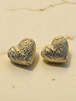 Close-up of gold-plated diagonal-ridged heart studs placed on a beige linen surface